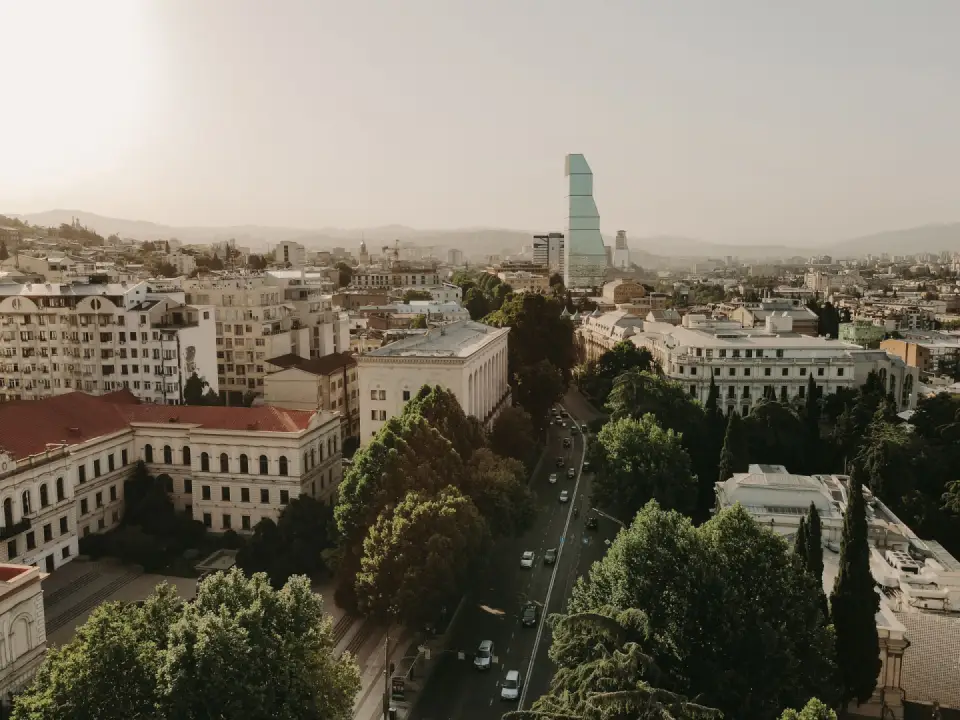 Aerial view of Tbilisi’s historic buildings, tree-lined streets, and distinctive modern architecture.
