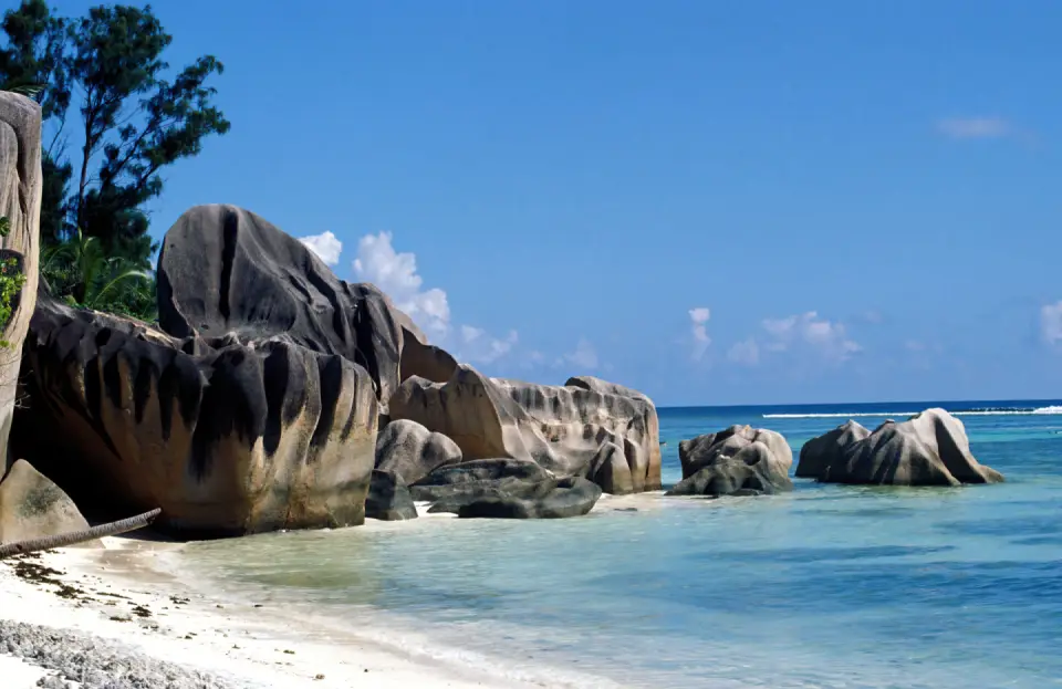 Pristine Seychelles beach featuring dramatic granite rock formations, white sand, and clear blue ocean water.